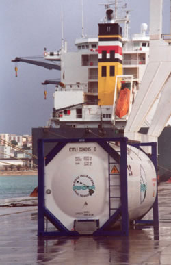 A Premier Tank Solutions tank container on the wharf beside a ship